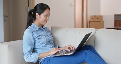 Woman working on laptop at home on couch