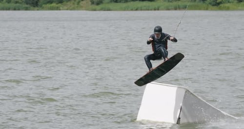 Wakeboarding in a Lake Near the Forest, Adult Man Surfs on the Water, Ride on a Wakeboarding Board