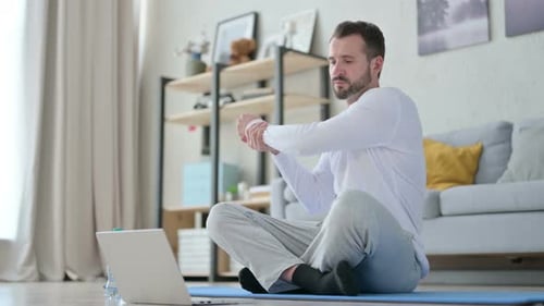 Man Stretching With Online Fitness Program at Home