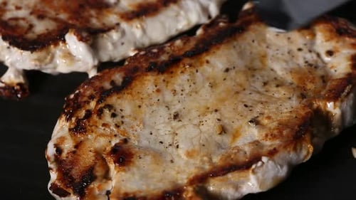 Pork Chop Sizzling on Grill Being Turned