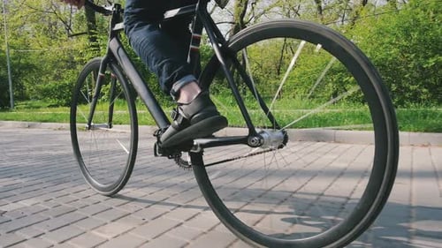 Travelling Shot d'un homme hipster faisant du vélo à pignon fixe dans un parc au Ralenti