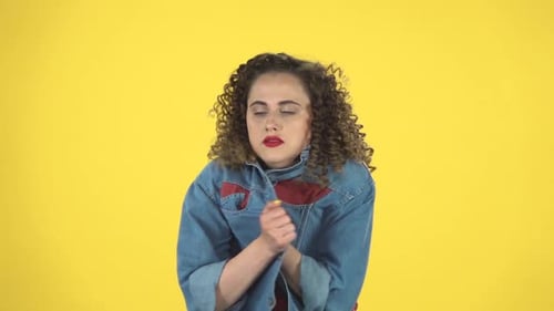 Belle fille gelée et essayant de se réchauffer sur fond jaune au studio, au Ralenti.