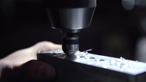 Pedaços torcidos de excesso de metal voam de um pedaço de alumínio durante o torneamento por meio de uma furadeira CNC. Corte fino