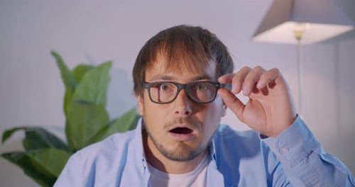 Man Takes Off Glasses with Shocked Expression