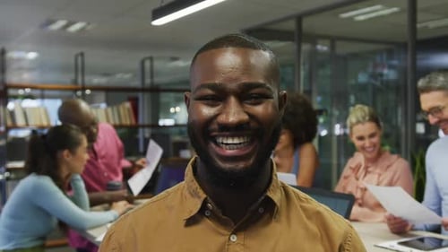 Smiling Man In Busy Modern Office Environment