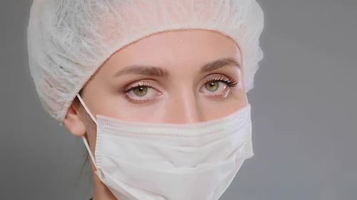 Gros plan du masque et de la casquette jetables Green Eyed Doctor in White