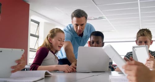 Lehrer unterstützt Schulkinder auf Laptop 4k