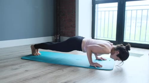 Shot Of A Young Female Athlete Performing Yoga postures at home on a blue mat to be fit