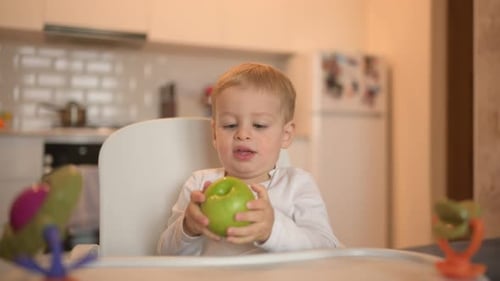 Child Sits in High Chair with Green Apple