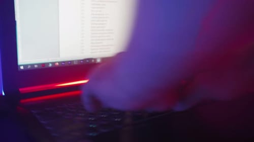 Hands Typing on Laptop with Neon Light