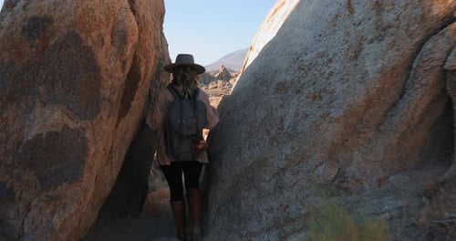 Junge lächelnde Frau mit Rucksack wandert bei Sonnenaufgang im malerischen Rocky Canyon
