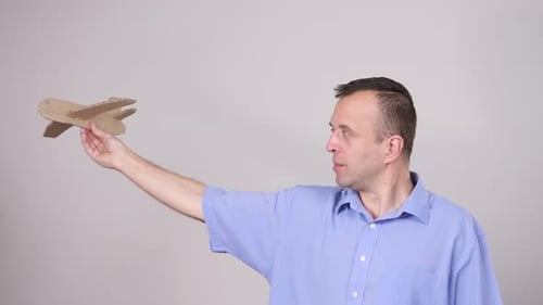 Man Holding Cardboard Airplane Toy Indoors