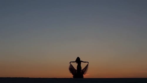Girl Is Dancing Belly Dancing Against the Beautiful Sunset on the Beach. Silhouettes