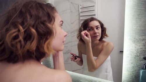 Woman Applies Makeup to Eyebrows in Mirror