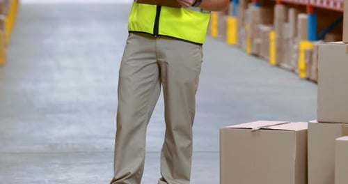 Male warehouse worker writing on clipboard