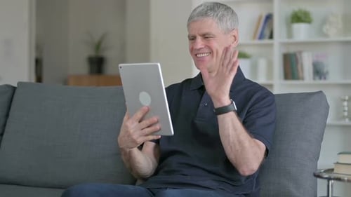 Mature Man Video Chats on Tablet at Home