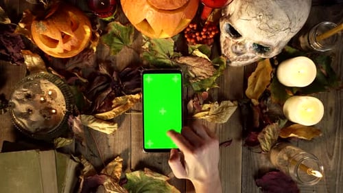 Gestures for Using a Vertical Smartphone on the Background of Halloween Decorations
