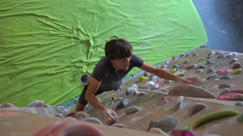 Young Man Is Climbing the Wall in a Bouldering Climbing Gym