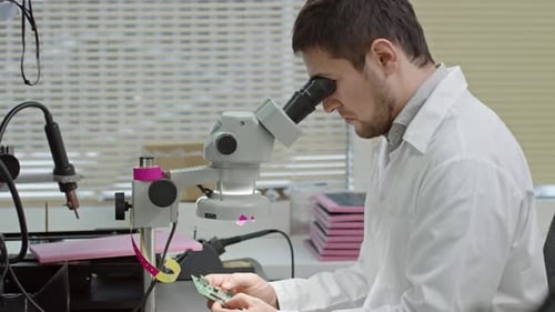 Man Inspects Circuit Board in Laboratory