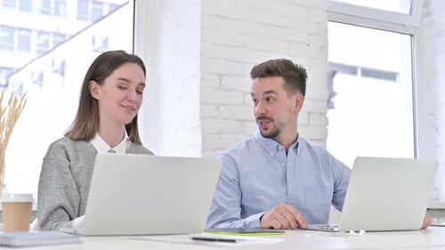 Coworkers Collaborating at Laptops in Modern Office