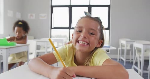 Video of happy caucasian girl sitting at school desk and learning