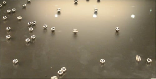 Metallic Spheres and Cylinders Rolling on Dark Surface
