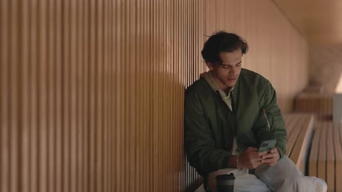 Young Man Uses Phone Sitting on Bench