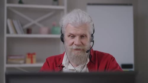 Senior Man Wearing Headset Speaking At Computer