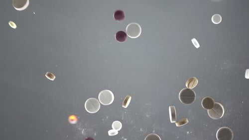 Mixed Pills on Grey Background Seen From Below Are Falling on Glass Surface in Slow Motion