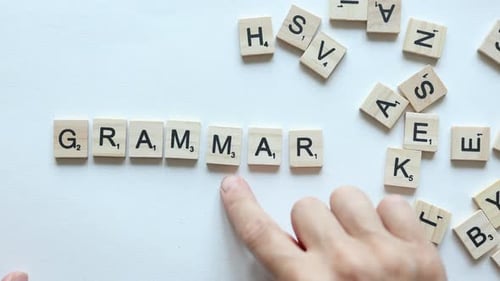 Hand Composing Word Grammar From Wooden Letters on White Background