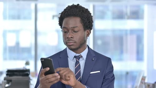 Man Celebrates Success Looking at Phone in Office