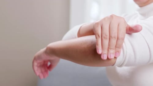 Mujer con dolor en el codo usa sus manos para masajearse para aliviar el dolor y ayudar a los síntomas