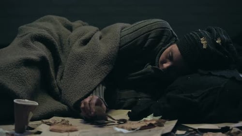 Homeless Person Sleeping on Cardboard at Night