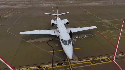 Man Removing Ice from Wing of Airplane