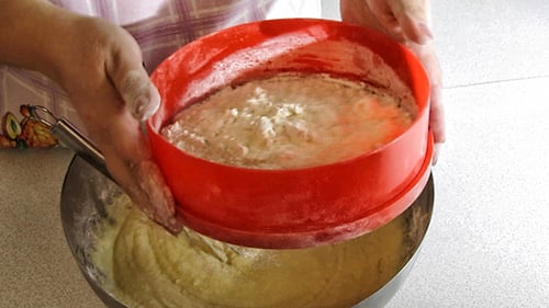 Hands Sifting Flour Into Batter in Kitchen