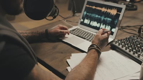 Tattooed Podcaster Editing Audio on Laptop