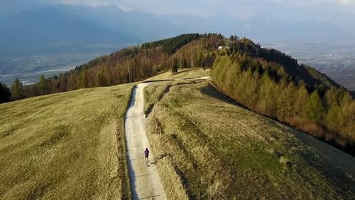 Aerial drone view of a man bike riding in the green countryside hills