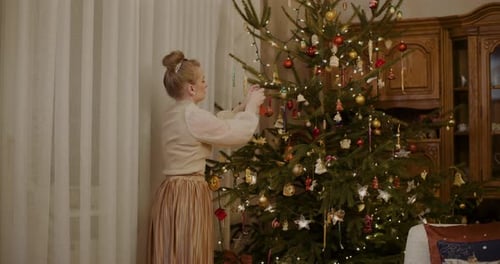 Woman Decorating Christmas Tree with Holiday Ornaments