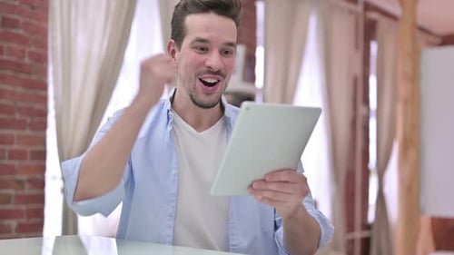 Young Man Excitedly Using Digital Tablet Indoors