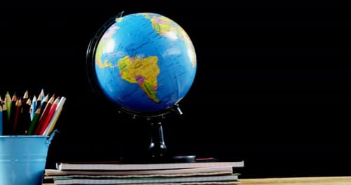 Globe and school supplies on table