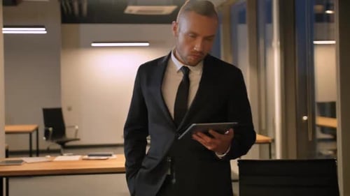 Man in Suit Uses Tablet in Office at Night
