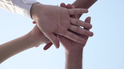 Nahaufnahme Handstapel multiethnischer junger Menschen mit klarem blauem Himmel im Hintergrund