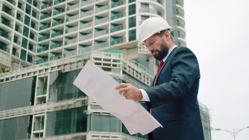 Caucasian Engineer Man or Architect Open the Paperwork Blueprint and Planning to Building