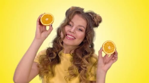 Woman Plays with Orange Halves on Bright Background