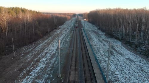 Passenger Train in the Winter Forest in the Evening. The Picturesque Landscape with the Railroad