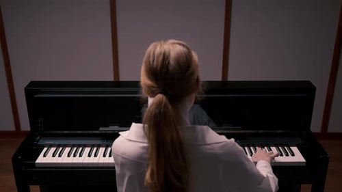 Woman sensually playing the piano view from the back