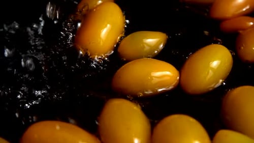 Falling yellow Cherry tomato into water