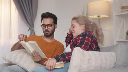 Young Couple Reading a Book Together on Couch