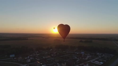 Heart Shaped Balloon at Sunrise Over Rural Landscape
