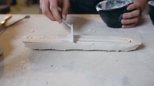 Des mains masculines qui mettent le mélange de gypse prêt à l'emploi dans les détails de la future sculpture